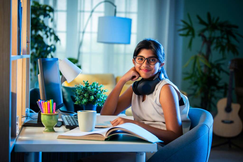 Indian asian teenage girl student using headphone and computer for studying at home