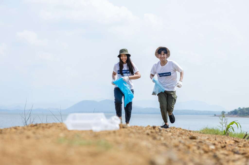 Male and female volunteers running to pick up plastic garbage. Conducting environmental cooperation,